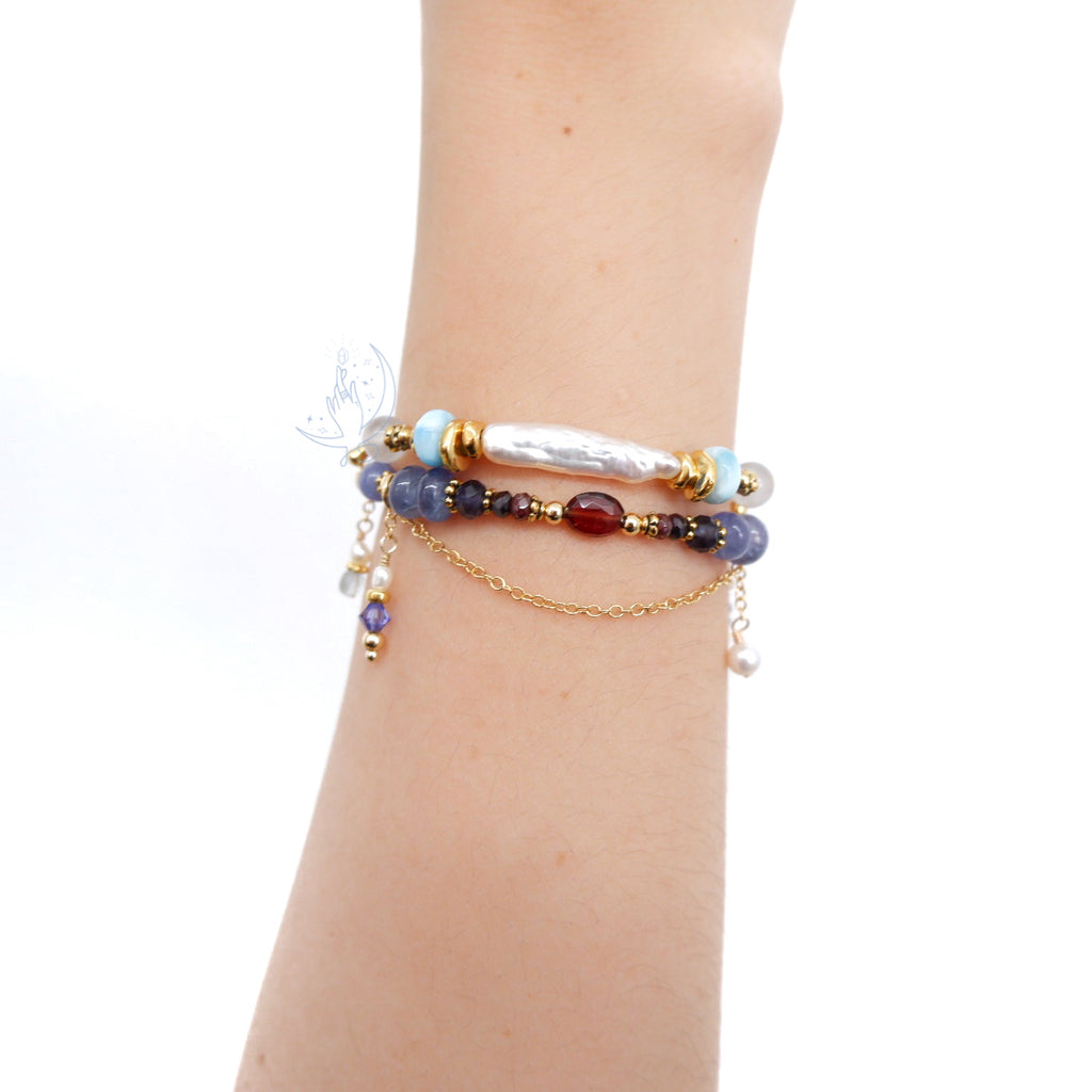ombre bracelet in shades of red, purple and blue, made with garnet, iolite, tanzanite and aquamarine, with aquamarine and swarovski crystal charm when worn with pearl bracelet