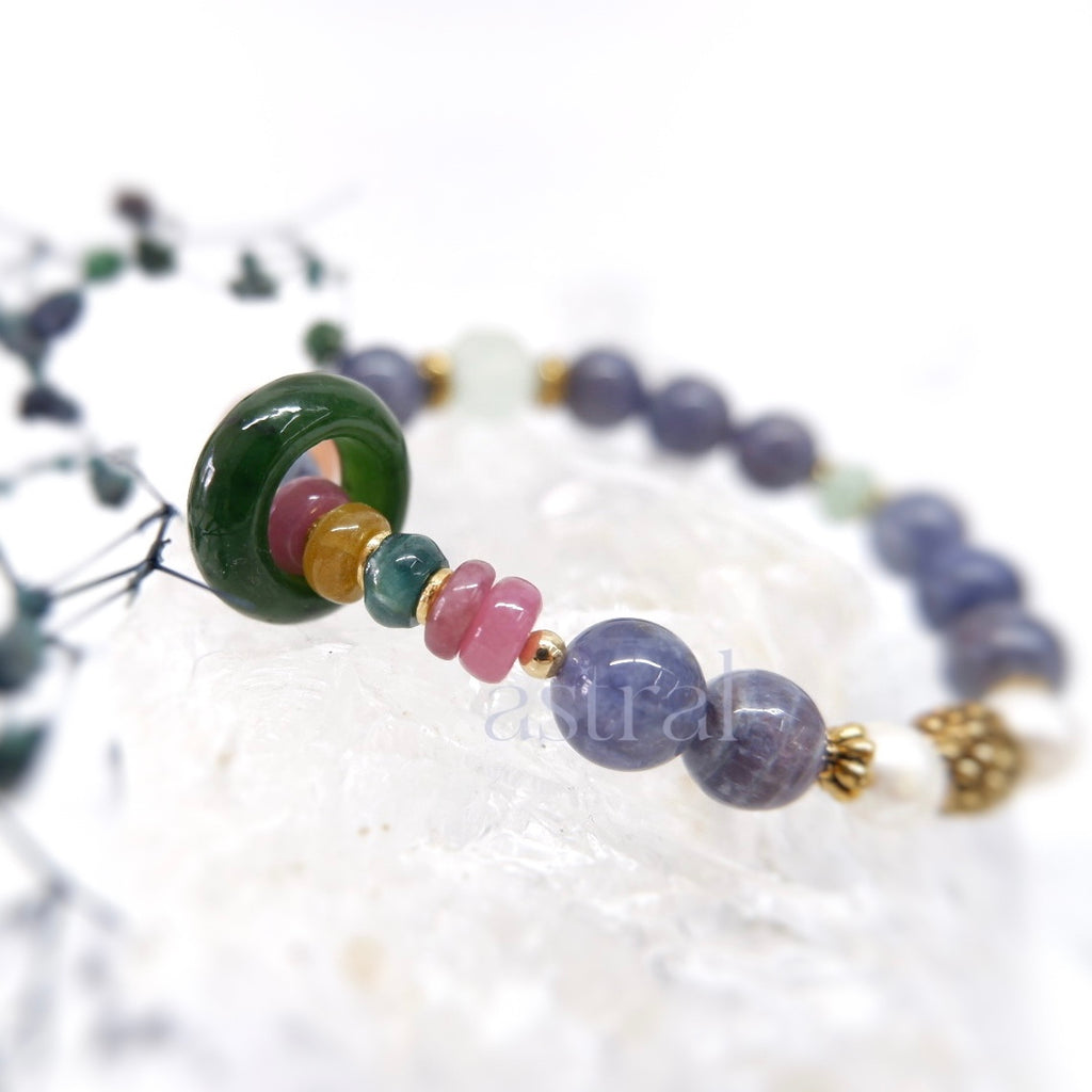Side view of foresight bracelet, featuring the rainbow tourmaline and runner bead against the iolite sunstone beads
