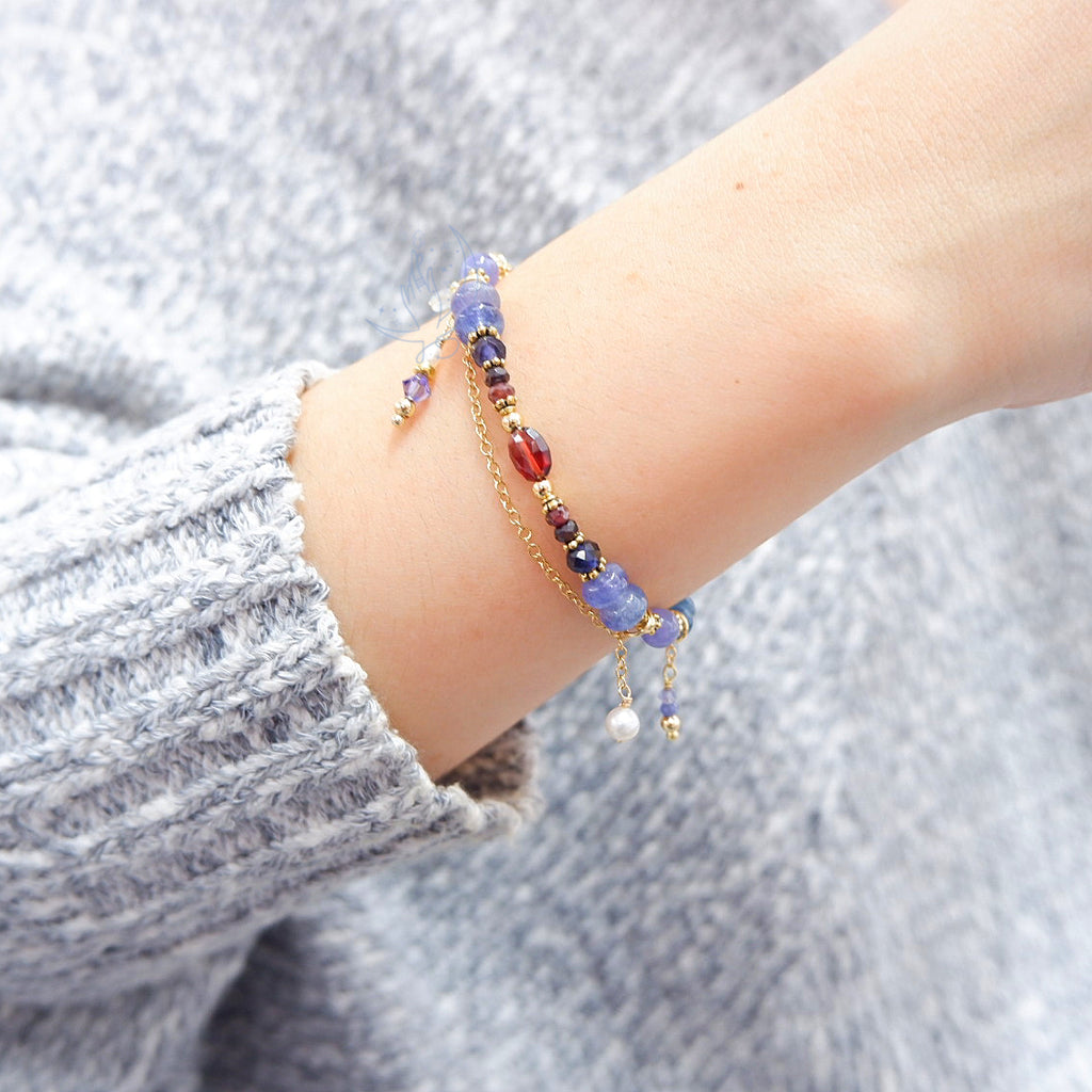 ombre bracelet in shades of red, purple and blue, made with garnet, iolite, tanzanite and aquamarine, with aquamarine and swarovski crystal charm when worn